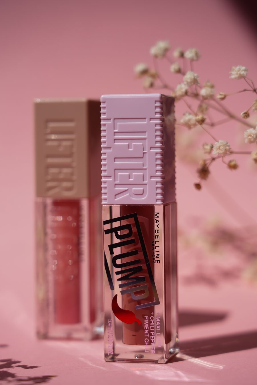 Lip glosses with pink flowers and a pink background — stock photo for Terms of Service