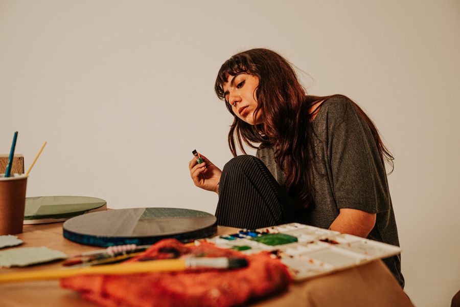 Contemplative female artist in studio setting — Design craft, taught with the product dashboard mockup