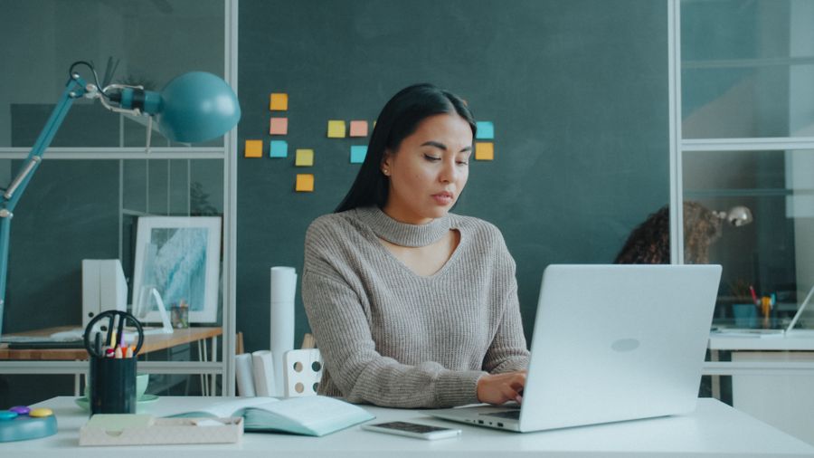 Focused woman working on laptop in modern office — Every photoaicompany design tool