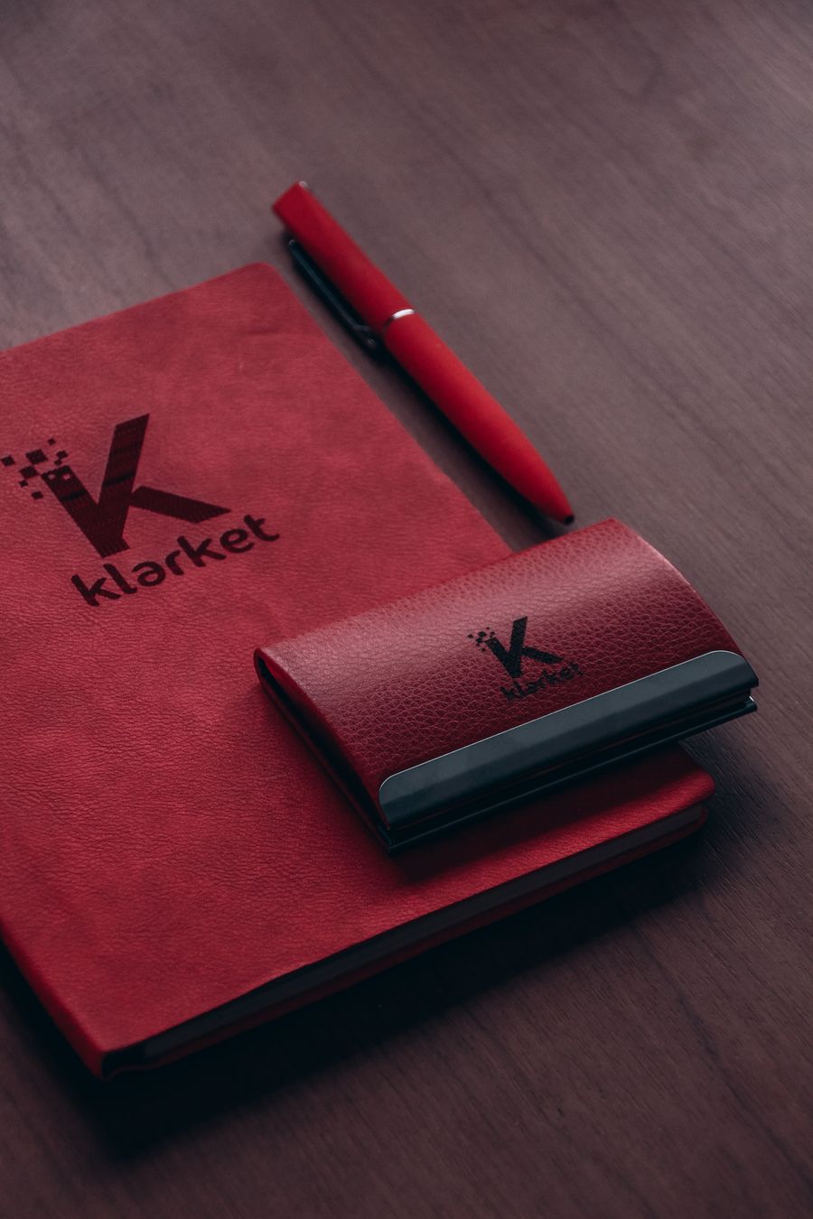 Klarket red leather pouch case and red notebook beside red pen — stock photo for Remove Background