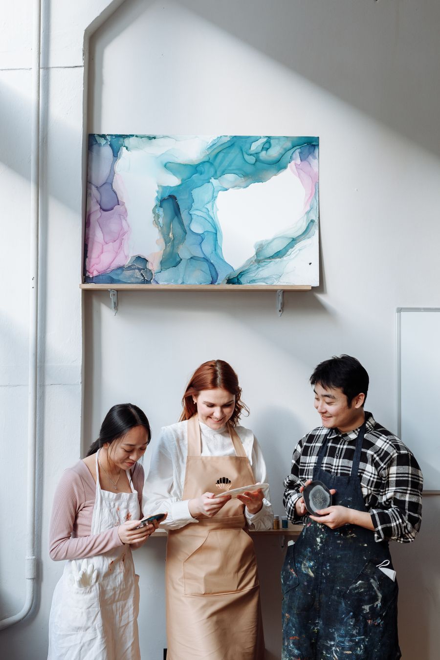 Smiling women and man standing under painting on wall — Pair display type with quiet body copy
