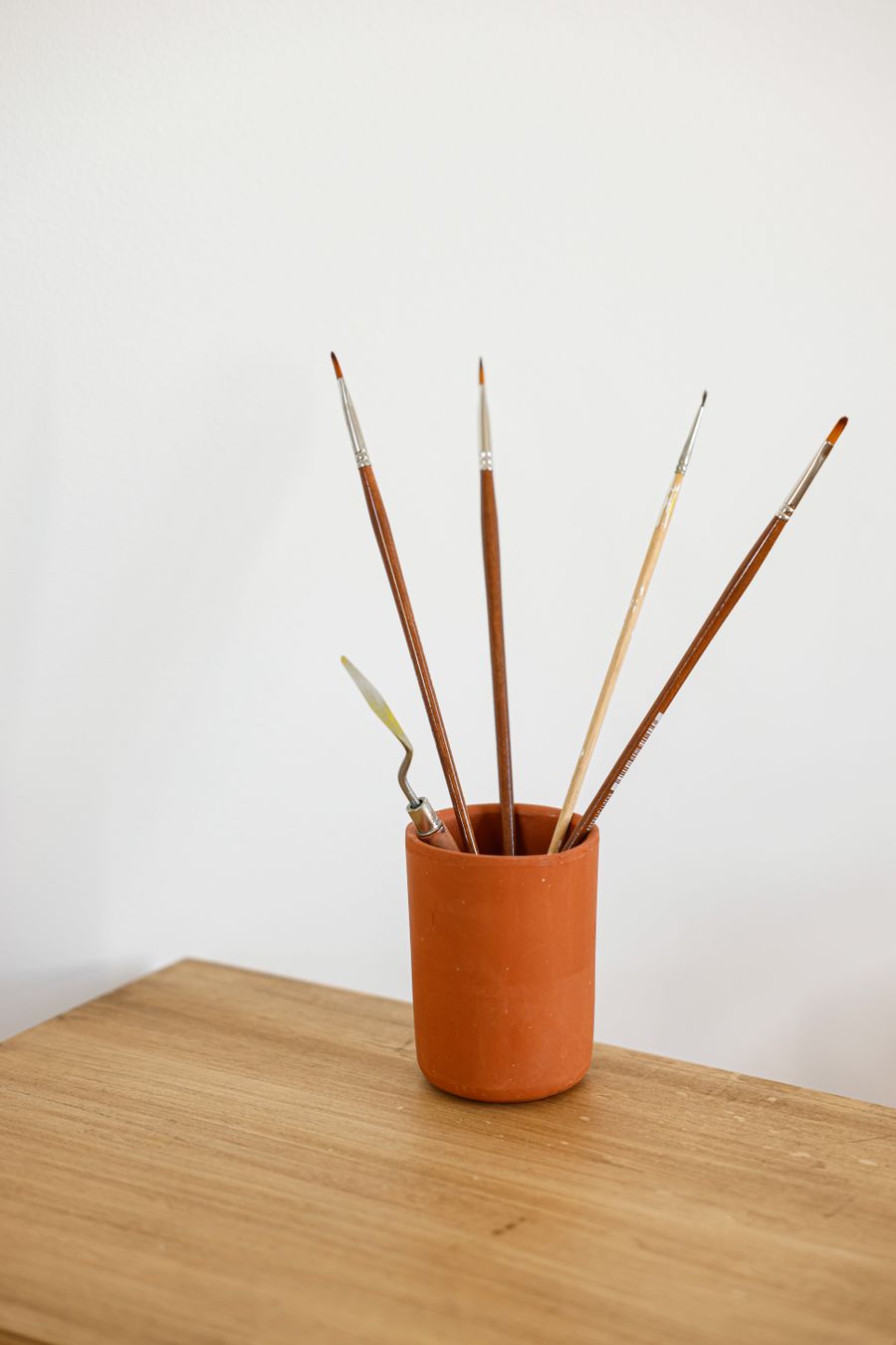 Paint brushes and a palette knife in brown ceramic cup on a wooden surface — Every photoaicompany design tool phone mockup