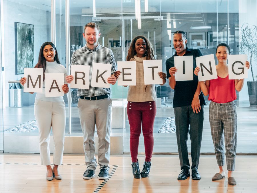 Happy coworkers holding up letters on pieces of paper — Documents annotated figure