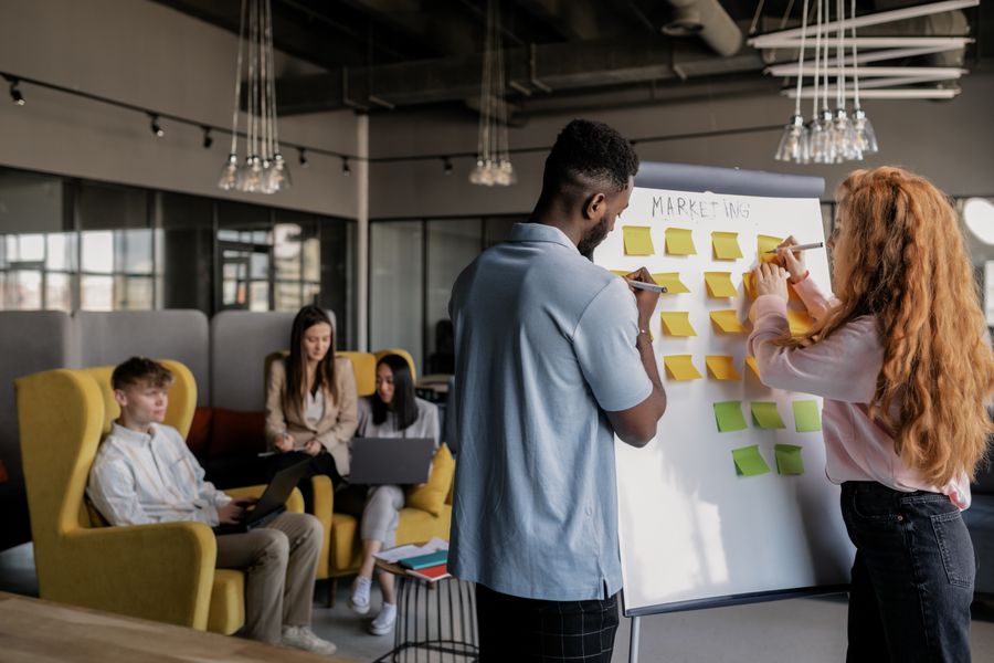 Photo of a man and a woman writing on a whiteboard with sticky notes — stock photo for Start designing free